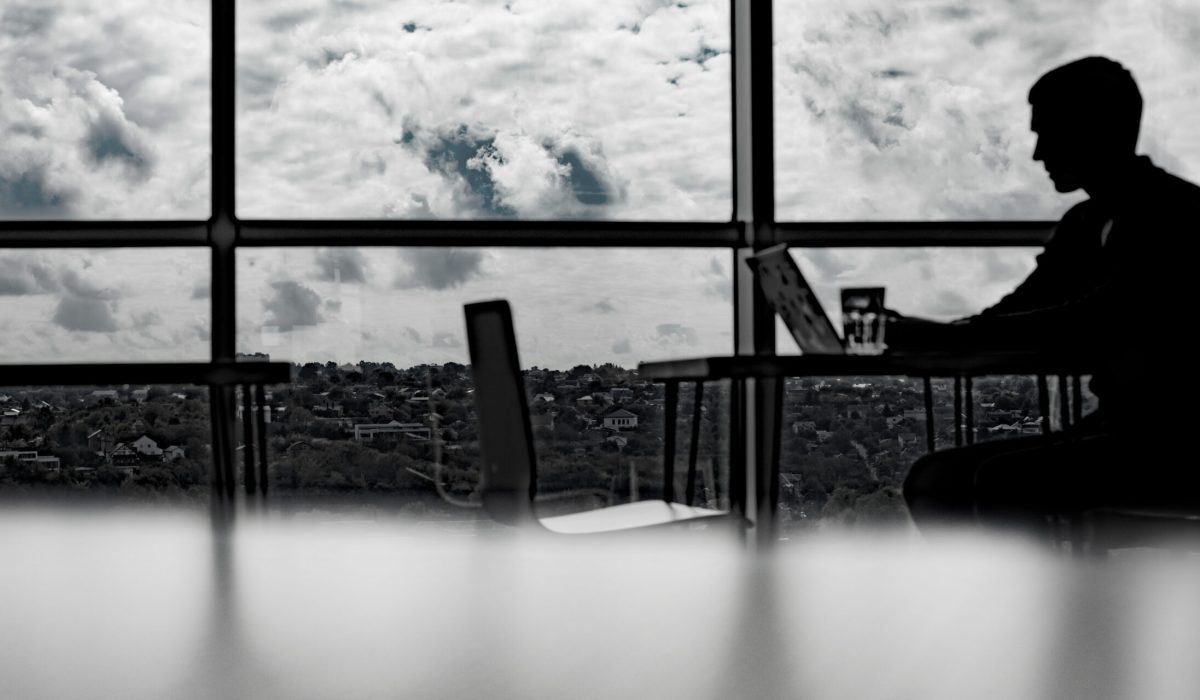 silhouette of a businessman working in an office with large windows.